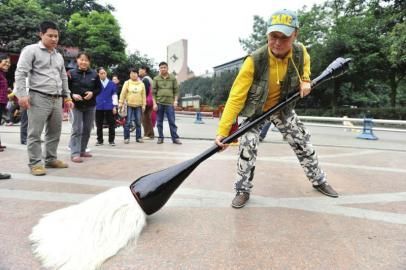 15日，成都市簇桥，胡光伍扛起70斤重的毛笔吸引了许多市民注意。