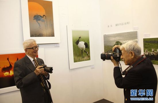 4月29日，87岁的台湾生态摄影家吴绍同(左)和90岁的“摄影老顽童”台湾摄影家秦凯(右)在自己的参展作品前拍照留念。